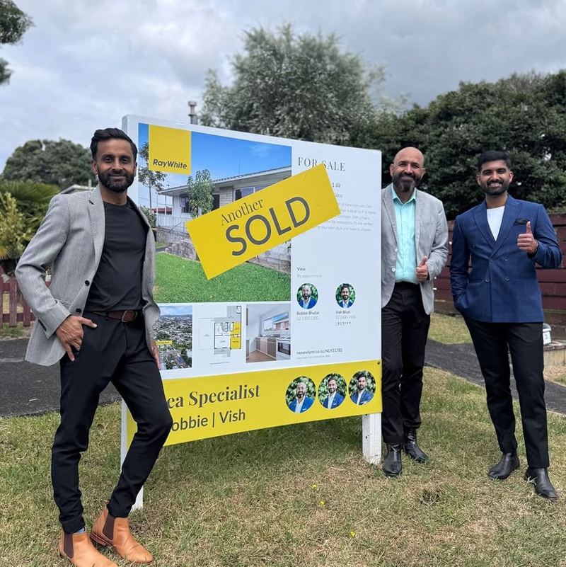 Area Specialist team with a Ray White SOLD sign outside a West Auckland family home